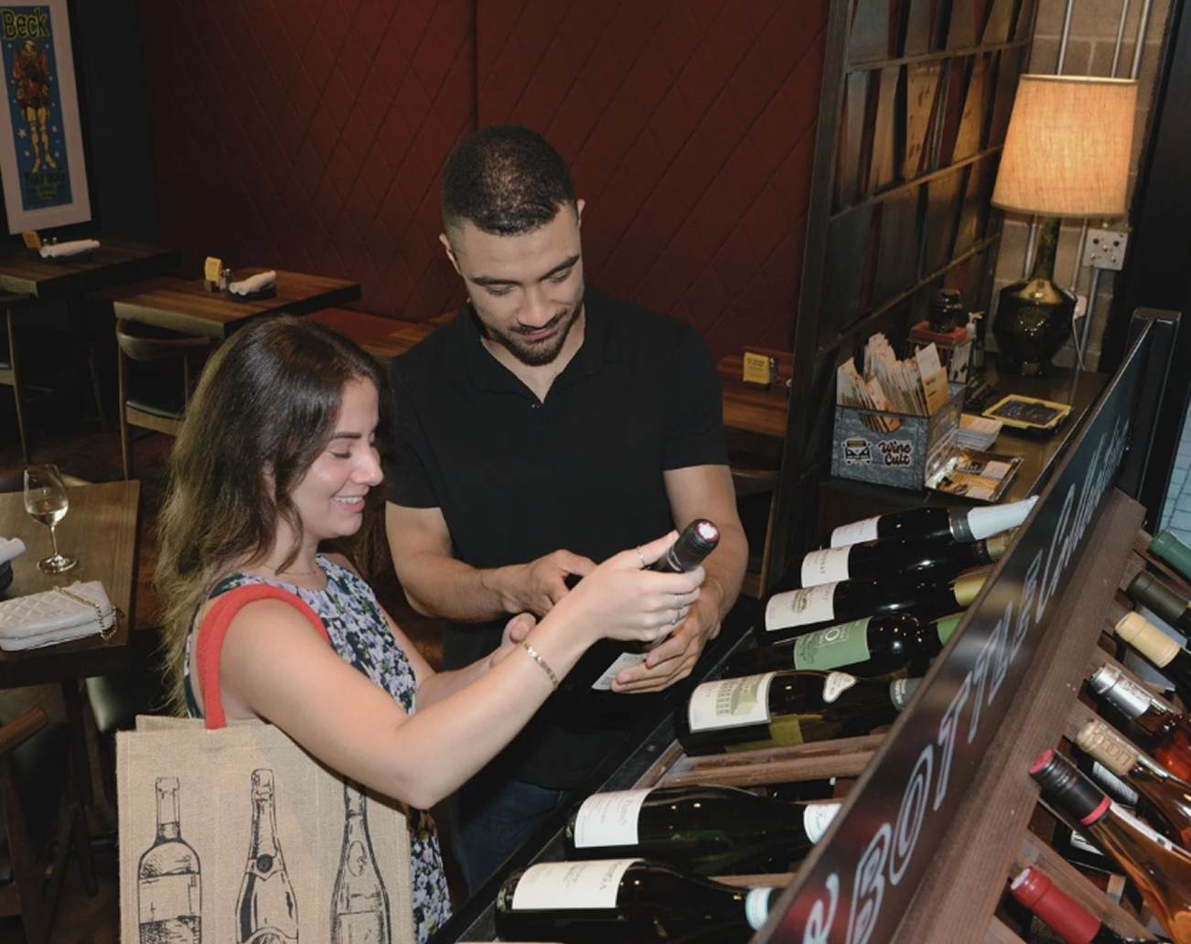 A couple shopping for wine at a store while carrying Shamajoy’s eco-friendly, reusable wine bag with a wine bottle print. The photo showcases the functional and stylish design of Shamajoy bags, perfect for wine lovers